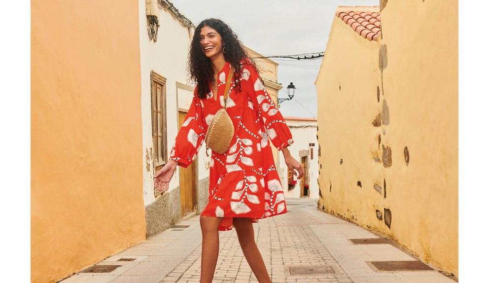 Woman in red printed linen dress walking across street